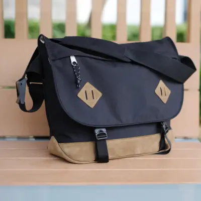 A-MoDe SC01 messenger camera bag in black nylon with tan suede trim on a bench