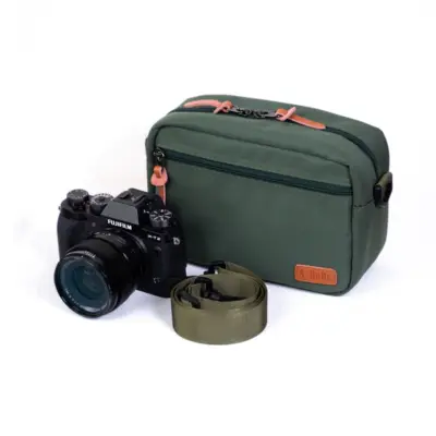 Olive drab A-MoDe SPX02 camera bag with a black Fujifilm mirrorless camera and shoulder strap